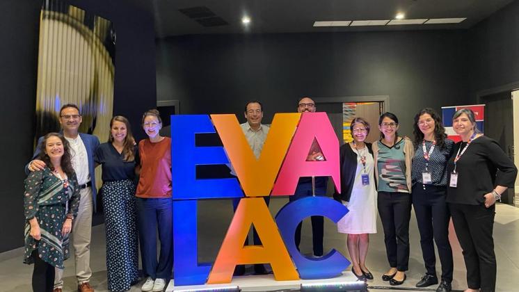 Group stands around EVALAC logo sculpture for photo.