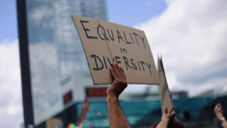 A hand holding a poster that says Equality in Diversity